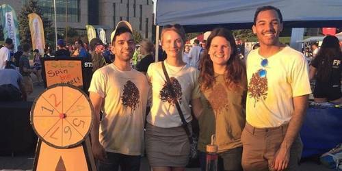 Four students smiling at a booth for the student environmental coalition